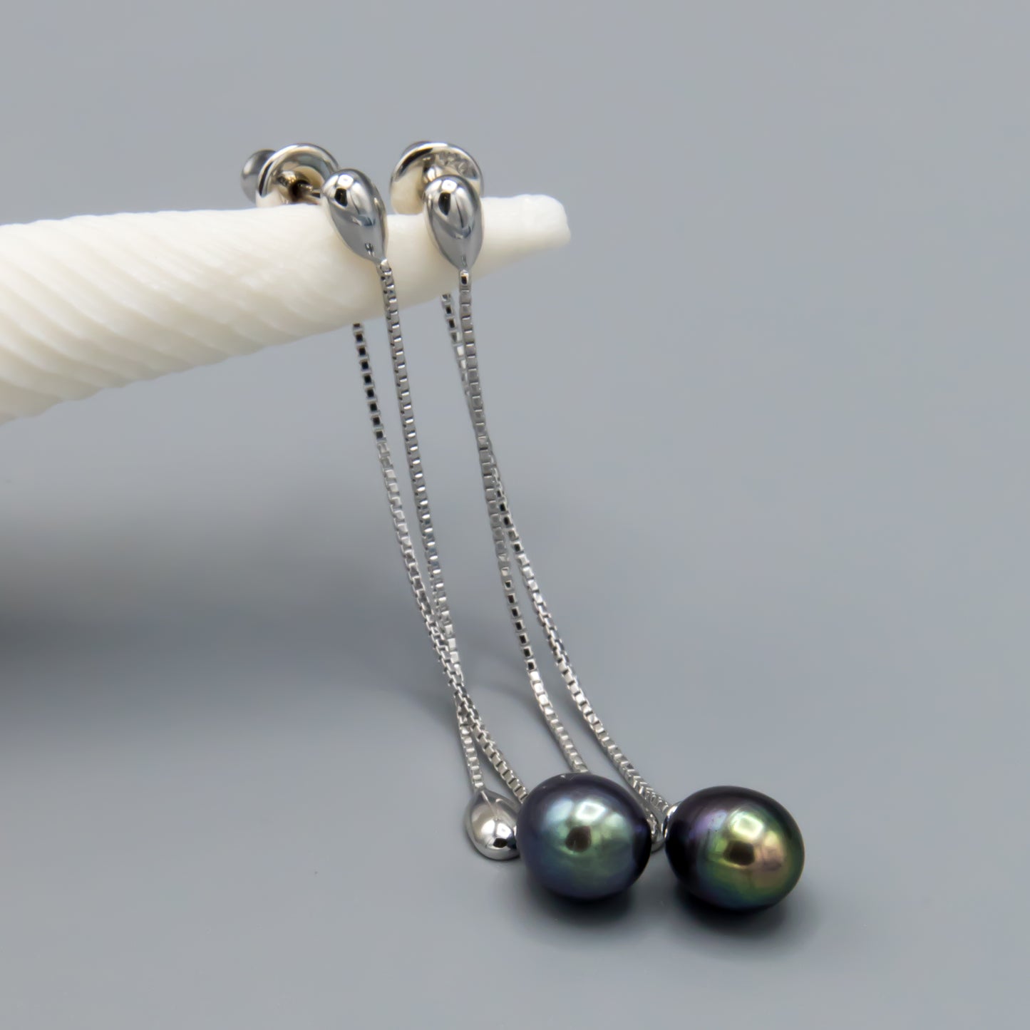 Pair of black teardrop pearl earrings demonstrating versatile styling options