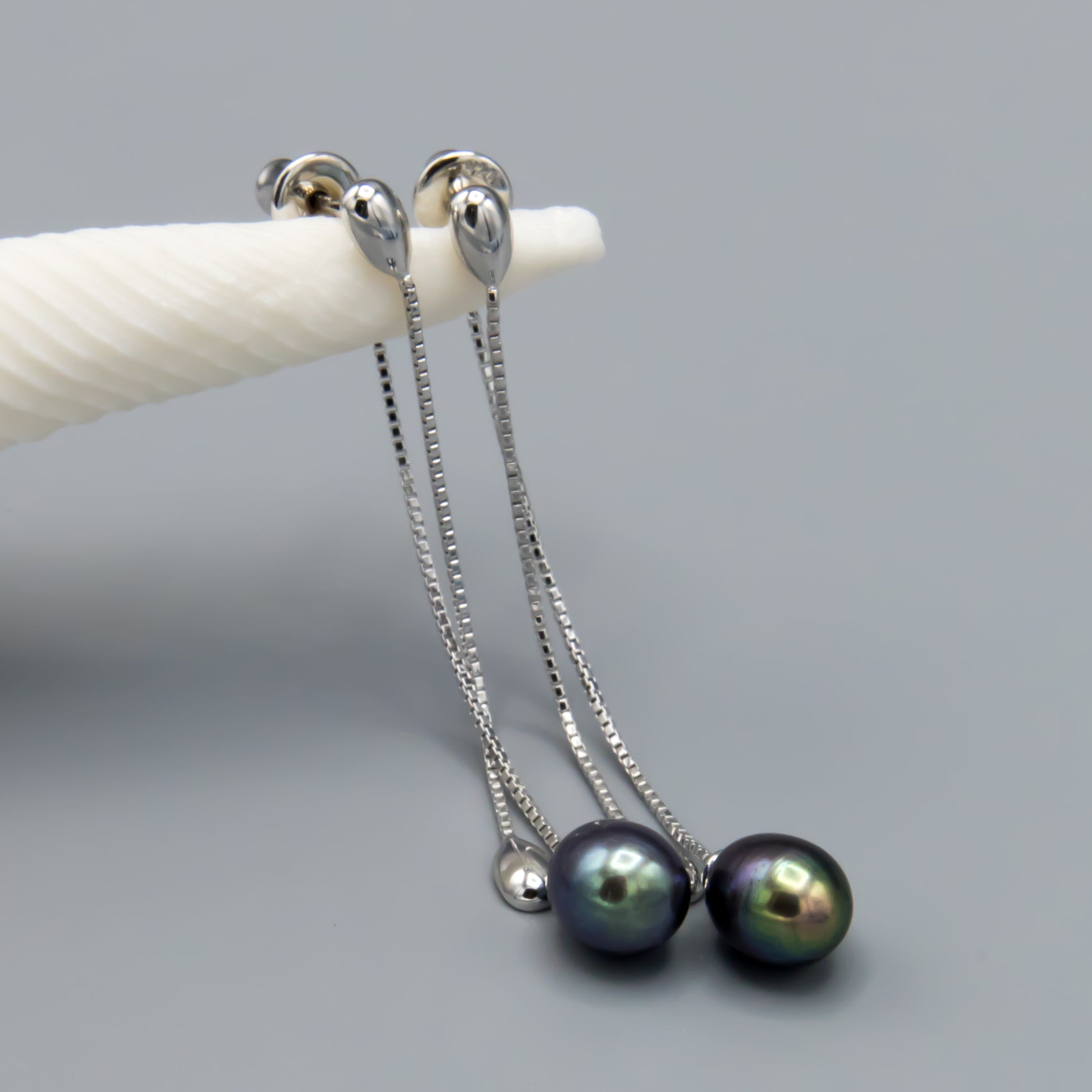 Pair of black teardrop pearl earrings demonstrating versatile styling options