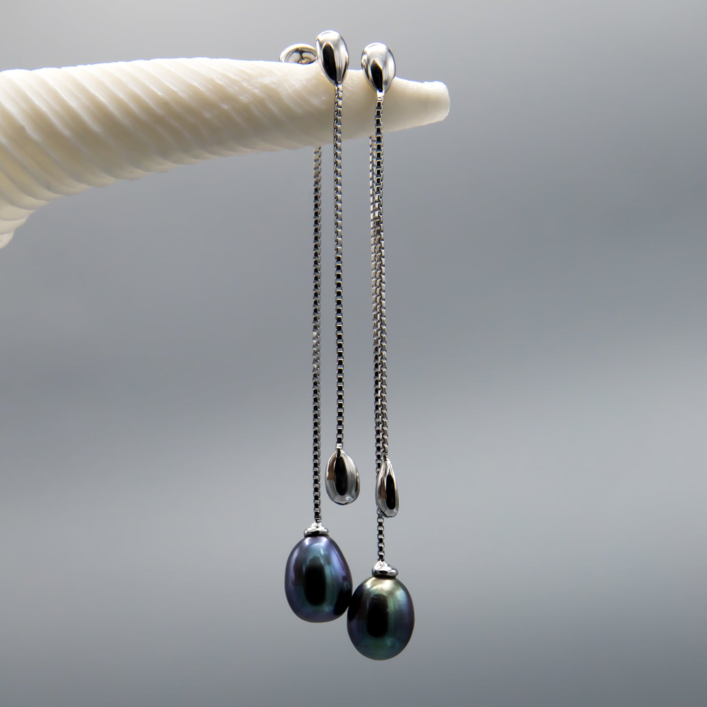 Sterling silver black pearl earring jackets worn, showing elegant dangle