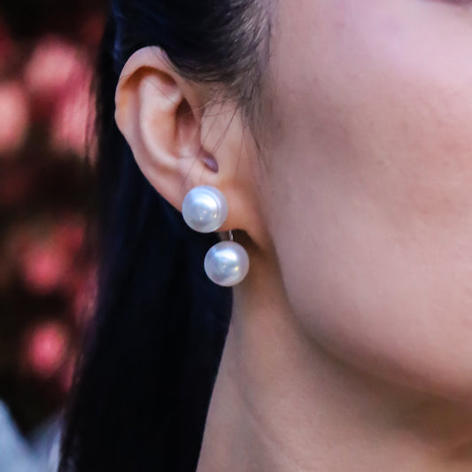 Close-up of a person wearing sterling silver baroque pearl earrings, organic natural shape with a blurred background