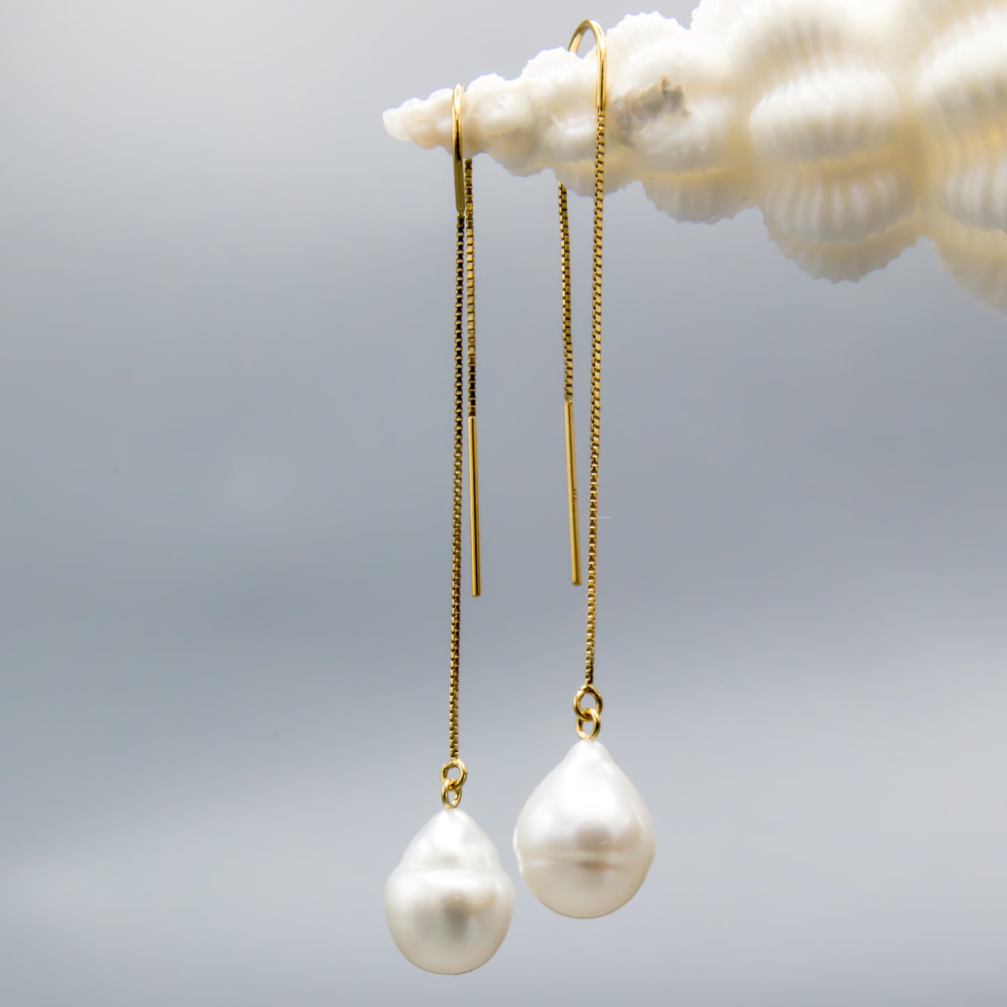 Close-up of baroque white South Sea pearl on 14K gold threader earring showing natural luster