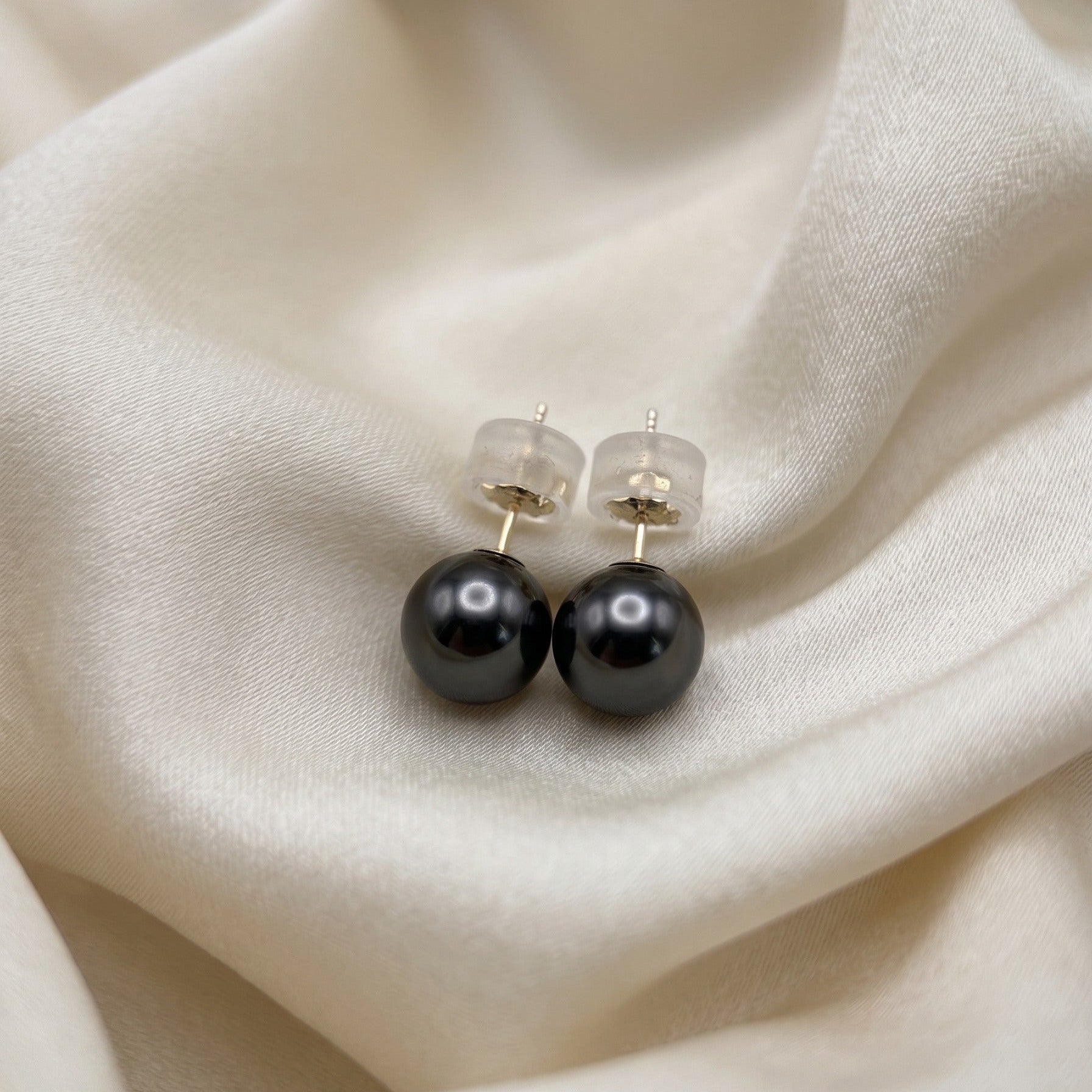 Close-up of 7.7mm Tahitian Pearl Studs, natural dark overtones, 14K yellow gold setting