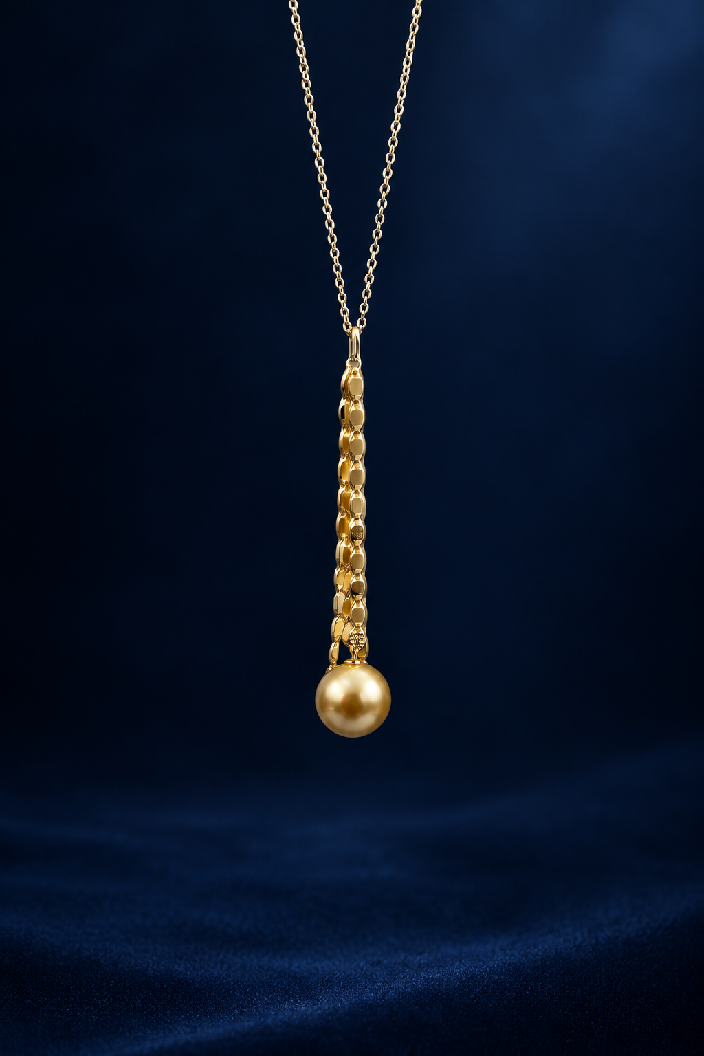Gold necklace with a single gold south sea saltwater pearl pendant on a blue velvet background