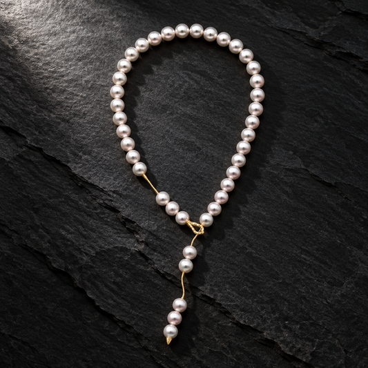 Holly Zhang Japanese Akoya saltwater cultured pearl lariat necklace styled as a loop with a cascading pearl drop and 14K yellow gold diamond clasp on a shale background