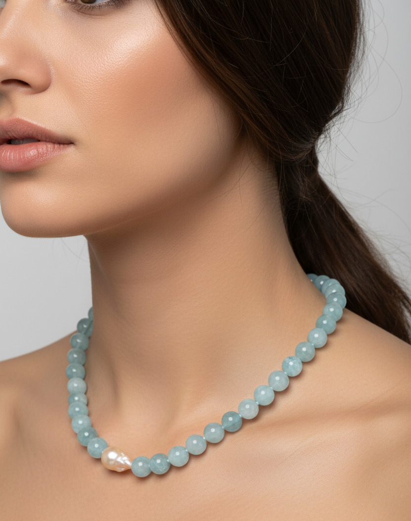 Model wearing aquamarine baroque freshwater pearl necklace, peach pearl detail at collarbone