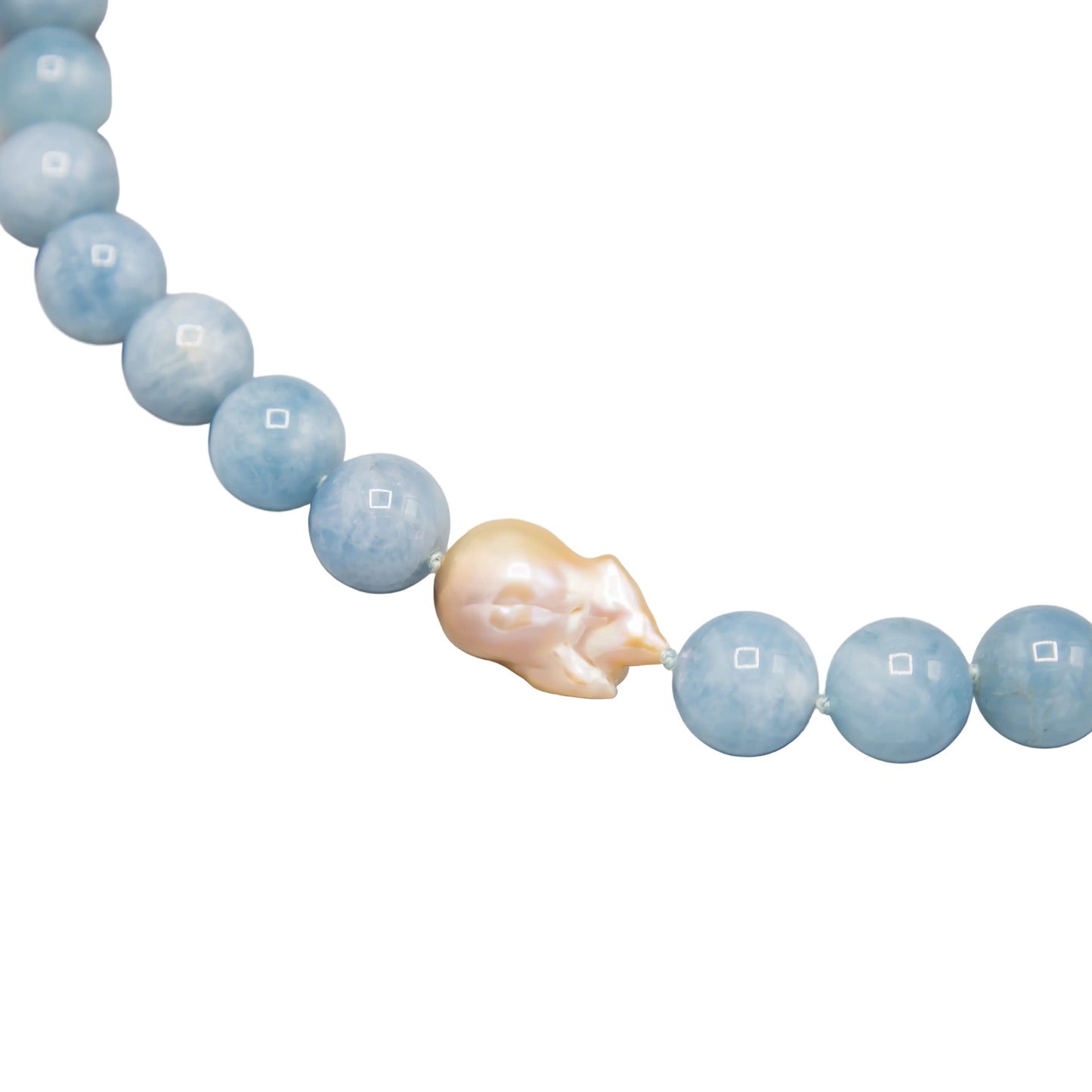 A necklace featuring light blue round aquamarine beads with a central iridescent peach-pink baroque freshwater pearl, photographed on a white background.