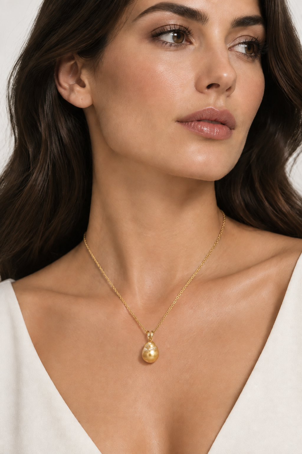 A woman wearing Golden South Sea baroque pearl pendant necklace worn on an 18-inch 14K gold chain.