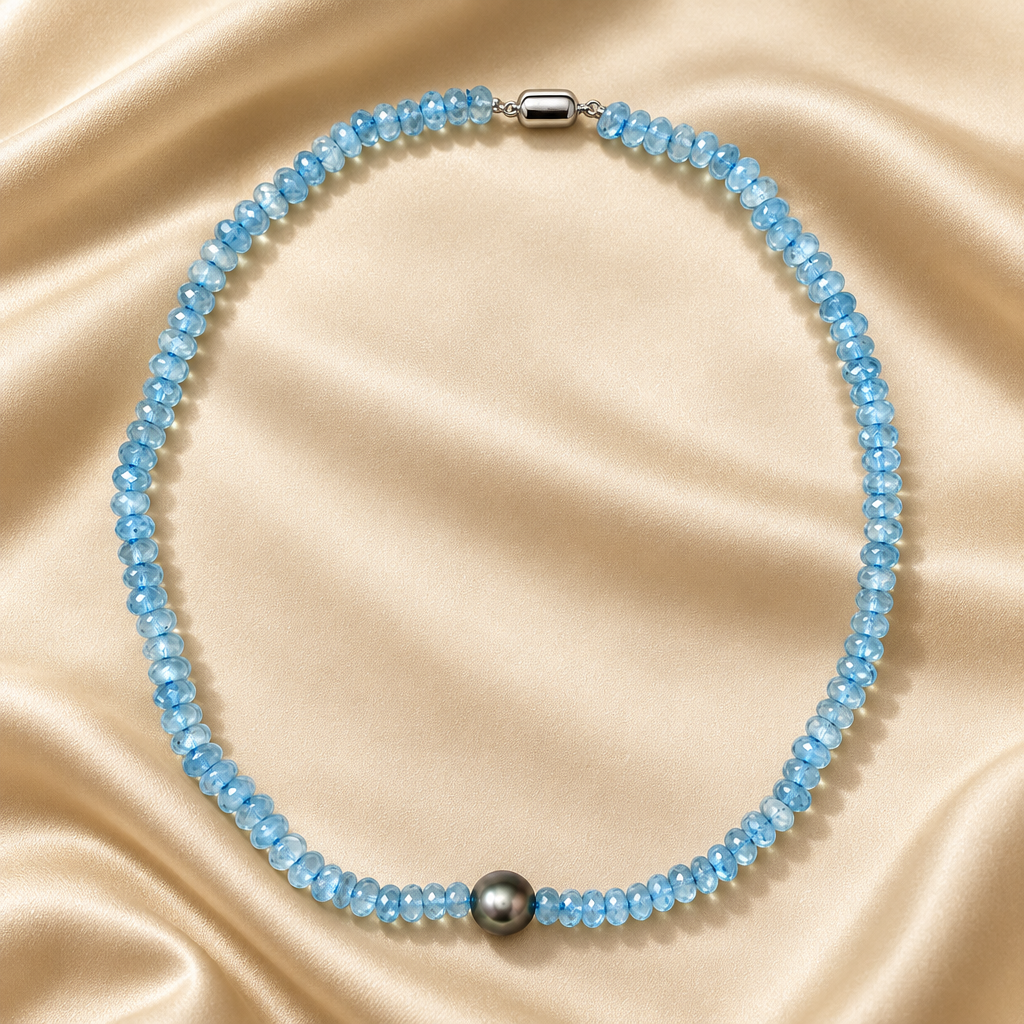 Aquamarine and Tahitian pearl necklace with blue faceted beads and a dark gray center pearl on champagne satin