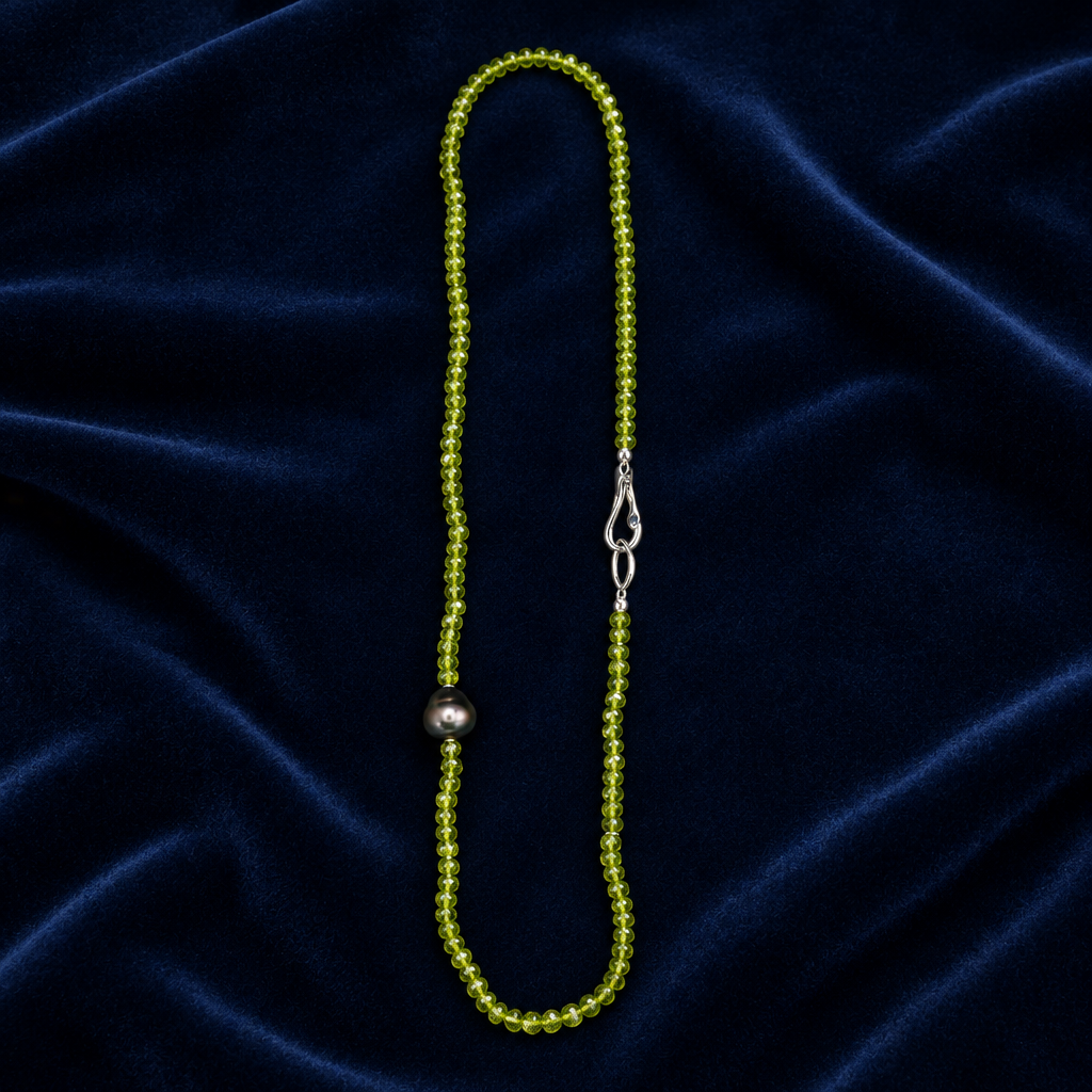 Peridot & Tahitian Pearl Necklace with green beads and a dark pearl on navy fabric
