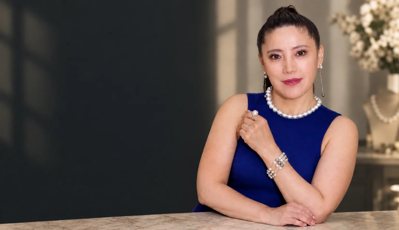 Holly Zhang, jewelry designer and founder, wearing a pearl necklace, ring and bracelet at her studio counter