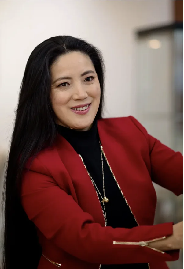 Holly Zhang in a red blazer, smiling in the gallery, from the Bellevue Downtown Association feature