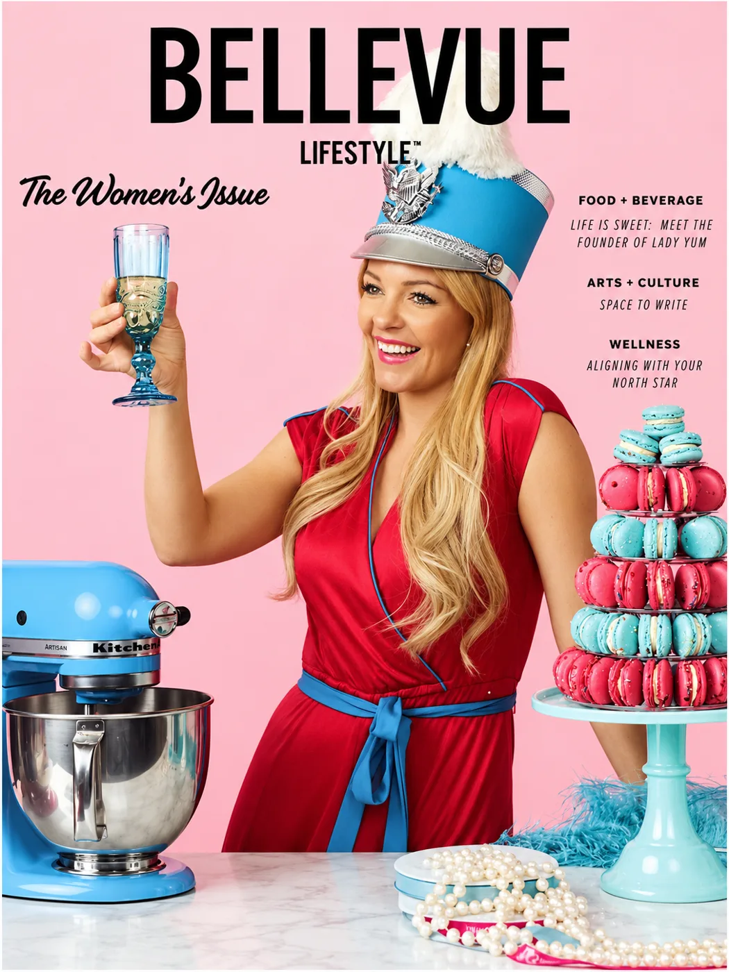 Bellevue Lifestyle cover, The Women’s Issue: a woman in a red dress raising a glass beside a tower of macarons and a strand of pearls