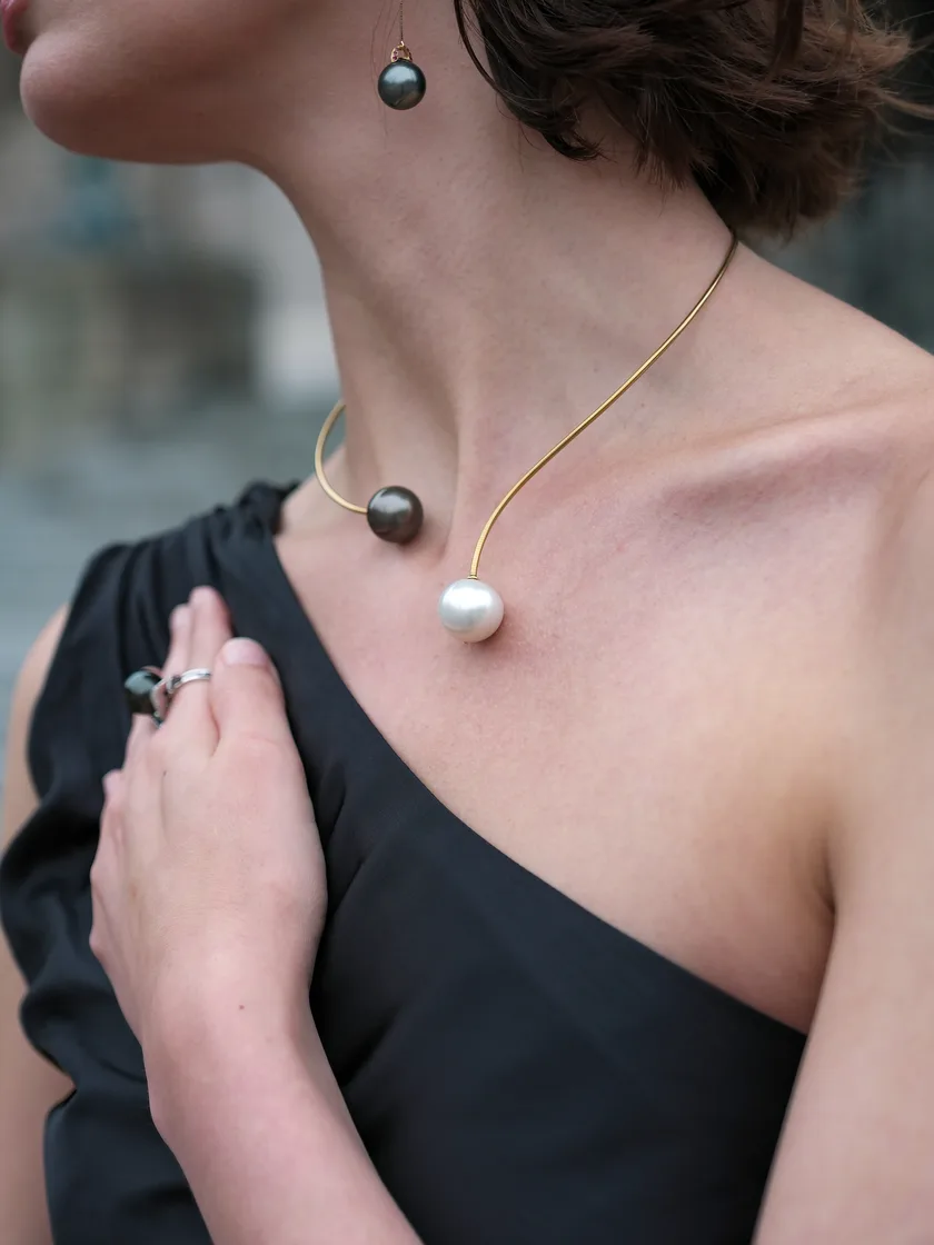 An open gold collar tipped with a Tahitian and a white South Sea pearl, with matching threader earrings