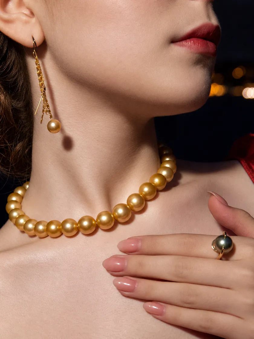 A golden South Sea pearl strand and a golden pearl chain drop earring, with a Tahitian pearl ring, worn with a red dress